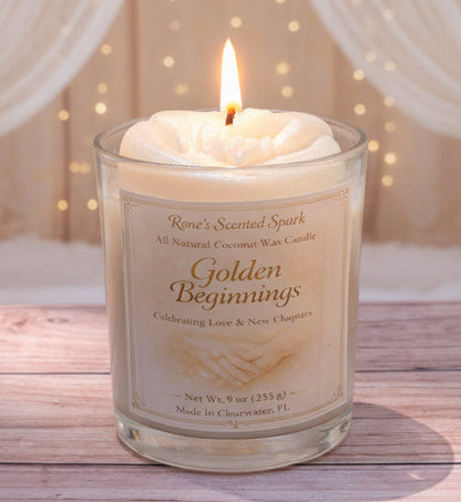 Candle labeled 'Golden Beginnings' on a wooden surface with a soft, blurred background
