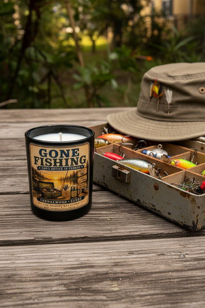 Gone Fishing Father's Day candle displayed next to an open vintage tackle box with fishing lures on a rustic wooden surface