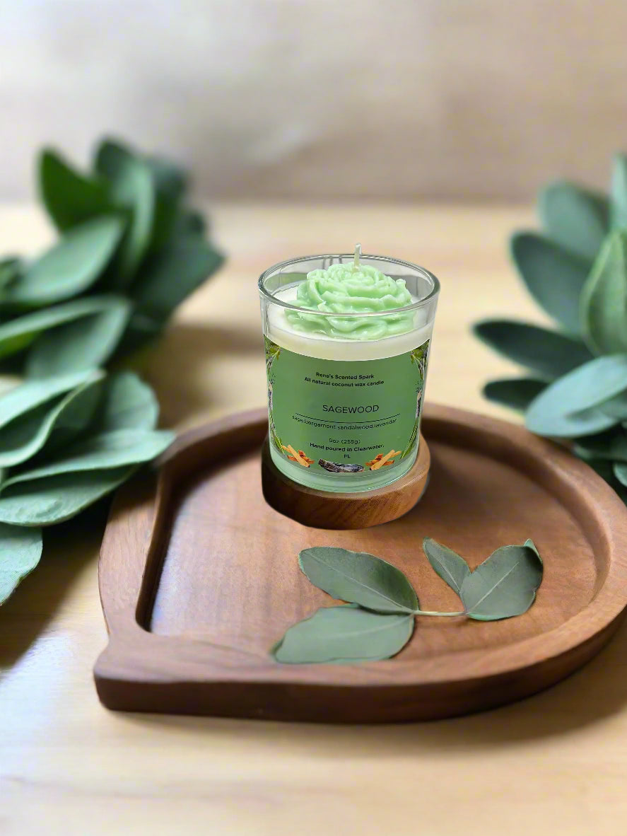 Sagewood candle glowing beside fresh sage leaves, lavender sprigs, and a wooden tray, creating a serene meditation space