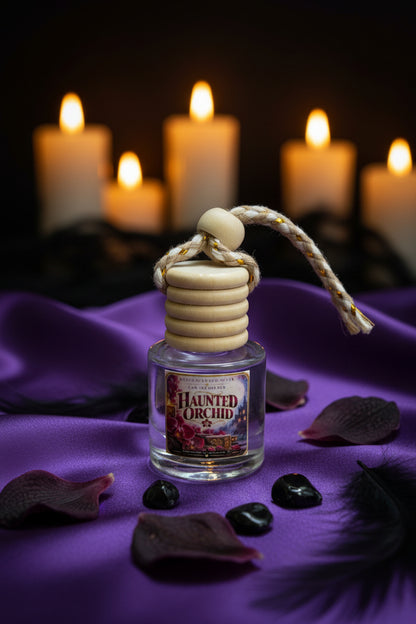 Haunted Orchid hanging car air freshener by Rene’s Scented Spark displayed on rich purple satin with dark orchid petals, black stones and softly glowing candles in the background.