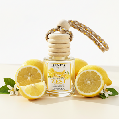 Simply the Zest lemon cake and vanilla hanging car freshener by Rene’s Scented Spark surrounded by fresh lemons and citrus blossoms. 🍋💛
