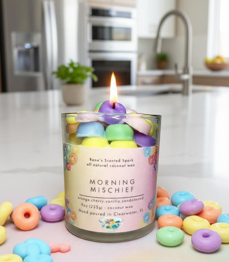 Morning Mischief coconut wax candle with colorful cereal-inspired wax pieces next to a bowl of fruit loops, evoking cheerful Saturday mornings.
