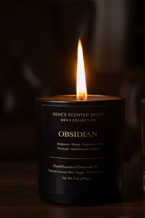 Candle with a pine cone on a dark forest floor