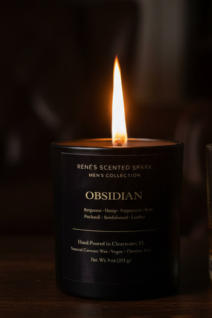 Candle with a pine cone on a dark forest floor