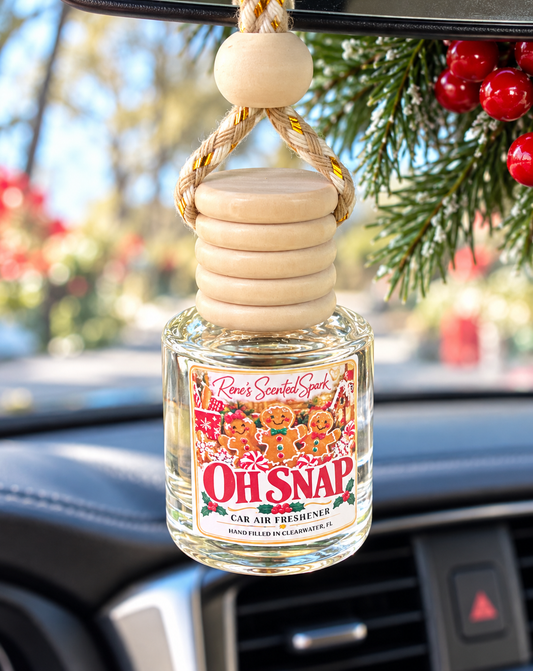 Oh Snap gingerbread car air freshener by Rene's Scented Spark hanging from a car rearview mirror with pine branches and red berries, Christmas car scent.