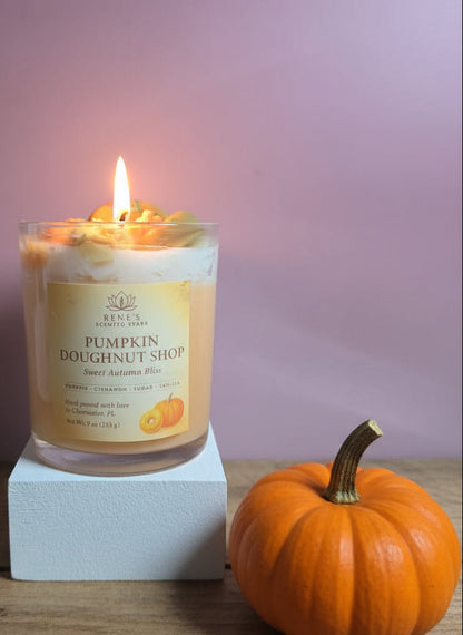 Candle in a glass jar labeled 'Pumpkin Doughnut Shop' with a pink background