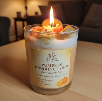 Candle in a glass jar labeled 'Pumpkin Doughnut Shop' by Rene's Scented Spark on a light purple background.
