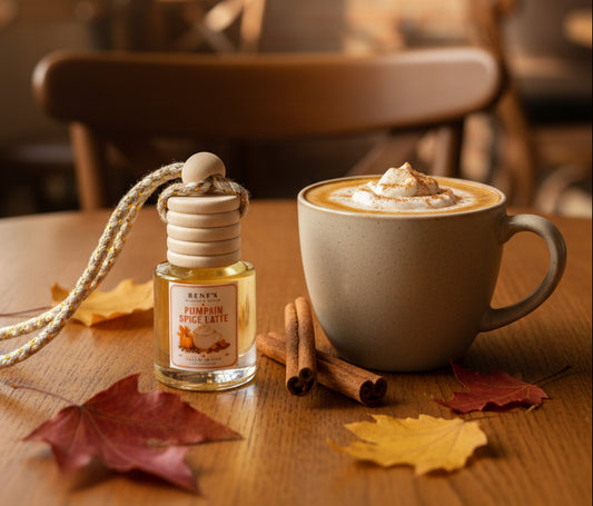 Pumpkin Spice Latte car freshener by Renes Scented Spark styled beside a warm latte with cinnamon sticks and autumn leaves in a cozy fall café setting.