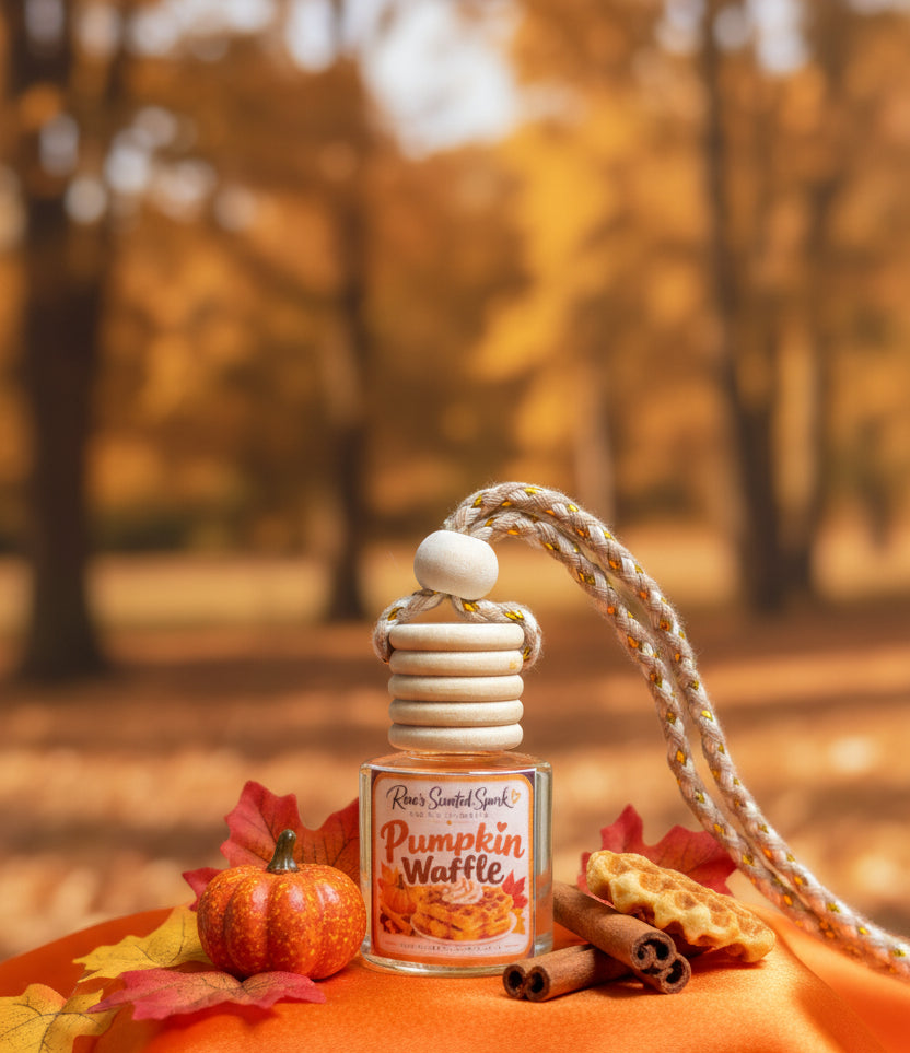 Pumpkin Waffle hanging car freshener by Rene’s Scented Spark styled with a miniature pumpkin, cinnamon sticks, waffle pieces, and autumn leaves against a warm golden fall background.