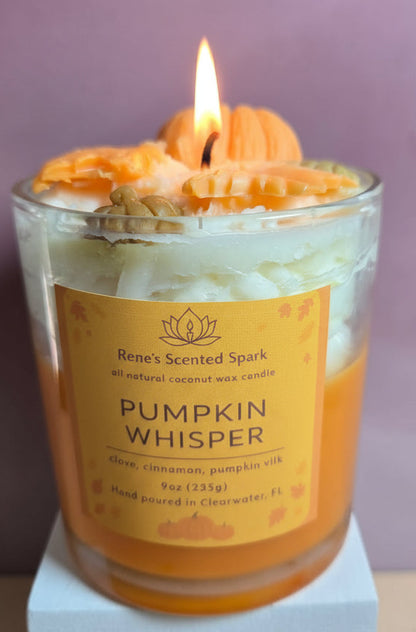 Candle with a pumpkin-shaped wick labeled 'Pumpkin Whisper' on a purple background