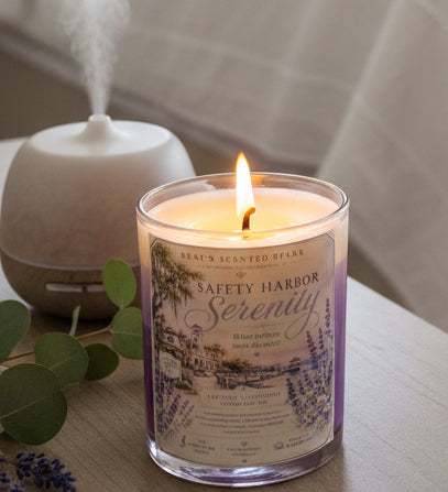 Lit Safety Harbor Serenity lavender coconut wax candle by Rene's Scented Spark displayed beside a misting essential oil diffuser and eucalyptus leaves, creating a calming spa-inspired setting.
