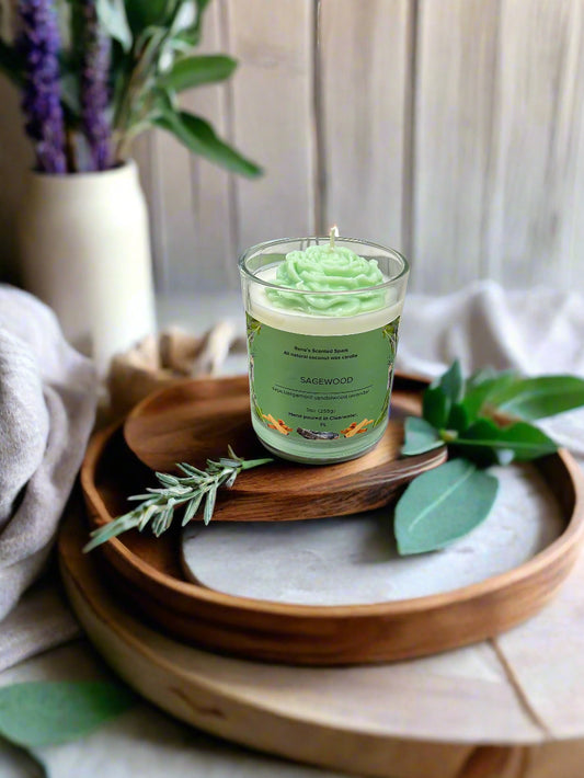 Sagewood candle glowing beside fresh sage leaves, lavender sprigs, and a wooden tray, creating a serene meditation space