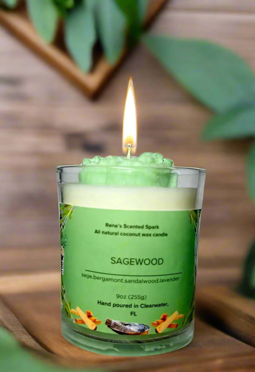 Sagewood candle glowing beside fresh sage leaves, lavender sprigs, and a wooden tray, creating a serene meditation space