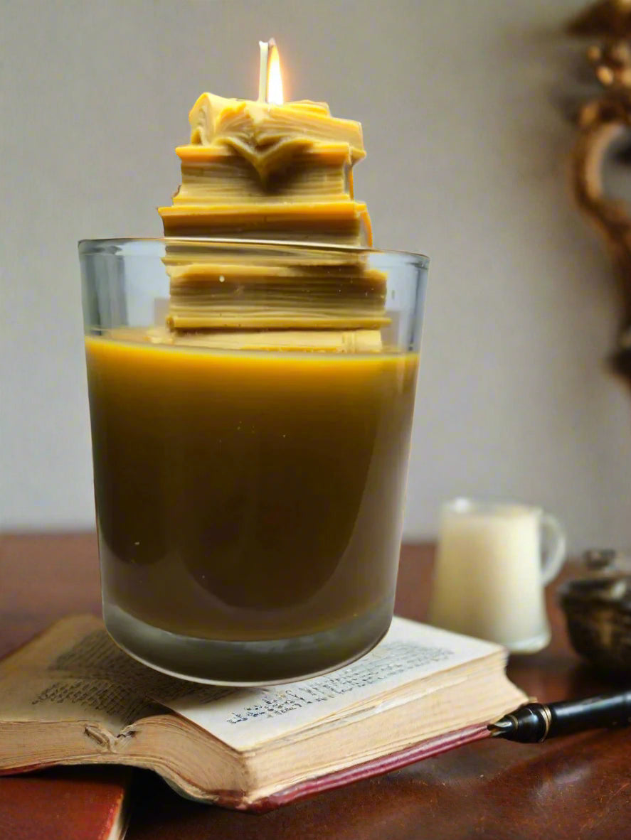 The Library candle with stacked book wax embed, hand-poured coconut wax with teakwood, cedar, leather, sandalwood, patchouli, and dark musk fragrance — perfect gift for book lovers