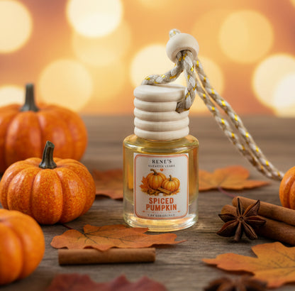 Spiced Pumpkin hanging car air freshener with wooden diffuser cap surrounded by orange pumpkins, autumn leaves, cinnamon sticks and star anise in a warm fall setting. 🎃🍂