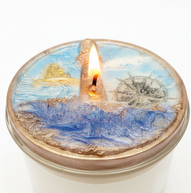 Close-up of a lit St. Augustine coconut wax candle featuring blue ocean-inspired wax, a compass design, and shimmering coastal details in a clear glass jar.