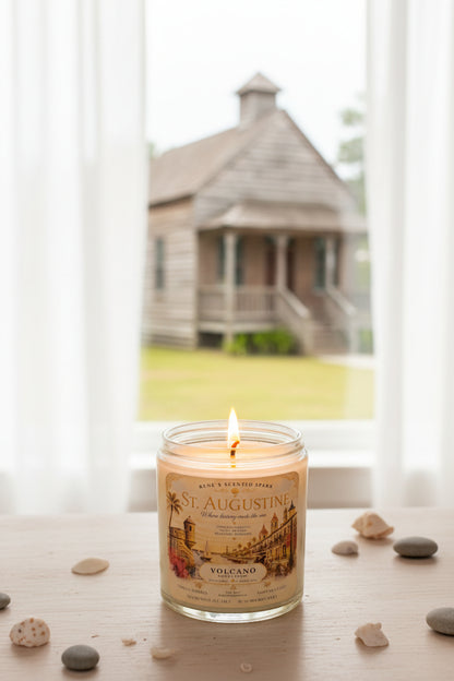 Lit St. Augustine coconut wax candle by Rene's Scented Spark displayed on a windowsill overlooking a historic wooden building, featuring a vintage-inspired Florida label in a cozy setting.