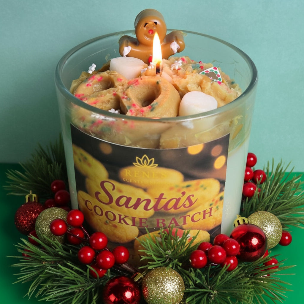 Decorative candle with gingerbread man and cookies, surrounded by Christmas ornaments and greenery.