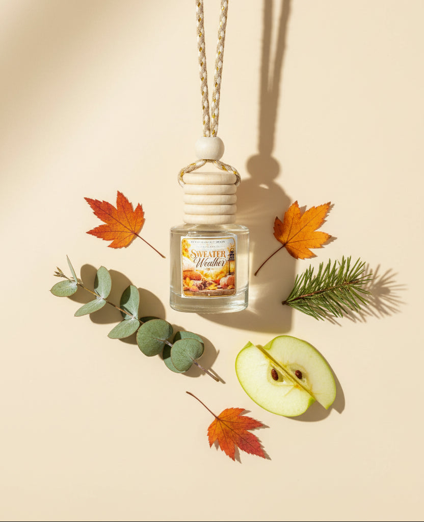 Sweater Weather car freshener by Rene’s Scented Spark displayed on a warm cream background with eucalyptus, pine, green apple, and autumn leaves.