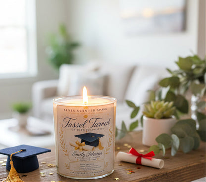 Handmade Tassel Turned graduation candle with a personalized graduate name displayed beside a graduation cap, diploma, and modern home décor. Premium coconut wax graduation gift hand-poured in Clearwater, Florida.