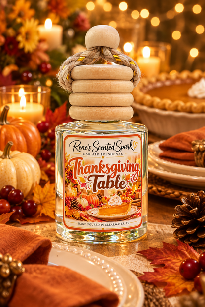 Thanksgiving car freshener on an elegant Thanksgiving dinner table with warm amber candlelight, cream plates, burnt-orange linen napkins, small pumpkins, autumn leaves, pinecones, cranberries, and soft golden string lights in the background.