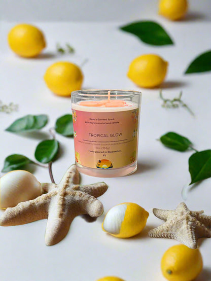 Tropical Glow coconut wax candle by Rene’s Scented Spark with a coral-colored wax top, in a glass jar with tropical floral label. Hand-poured in Clearwater, FL. Scented with mandarin, cassis, coconut, jasmine, sandalwood, and musk. Gift-ready tropical candle