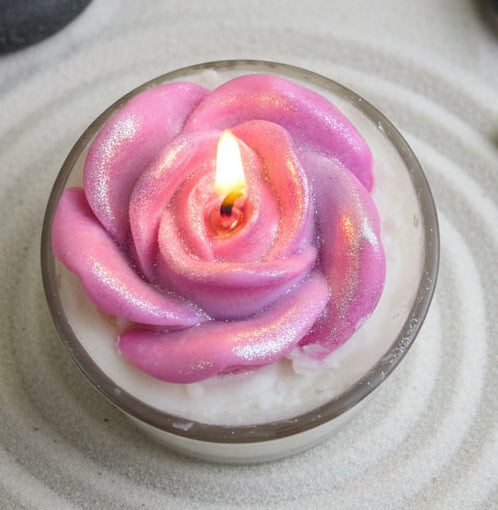 Top view of lavender vanilla coconut wax candle with pink rose wax melt and glowing flame in spa setting